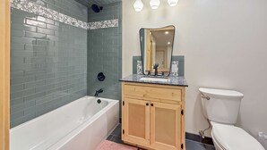 Un baño con bañera, tocador, espejo y retrete.