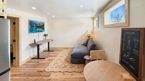Ein modernes Wohnzimmer mit einer Couch, einem Esstisch, einer Lampe und einer Kreidetafel-Speisekarte.