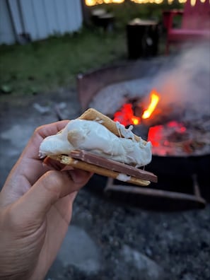 Una mano sosteniendo un sándwich de malvaviscos con una barra de chocolate.