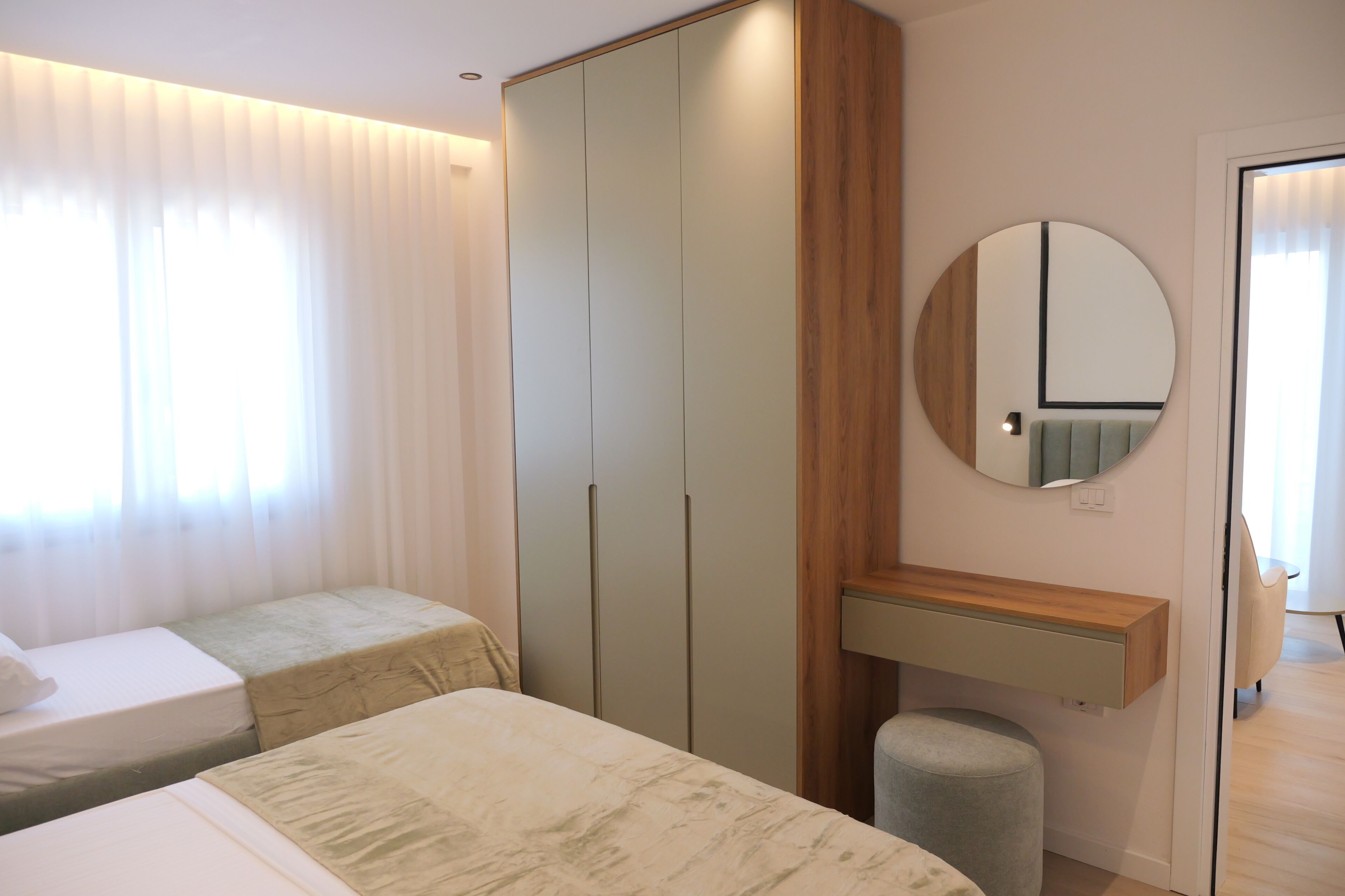 Une chambre avec deux lits, une armoire, un miroir et une table de chevet.