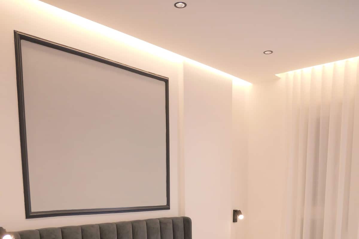 A modern bedroom with a bed, a bedside table, and a large framed picture on the wall.