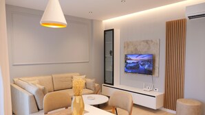 A modern living room with a sofa, a dining table, chairs, a TV, and a decorative vase. - Horizont Premium Apart-Hotel (Shkodër)