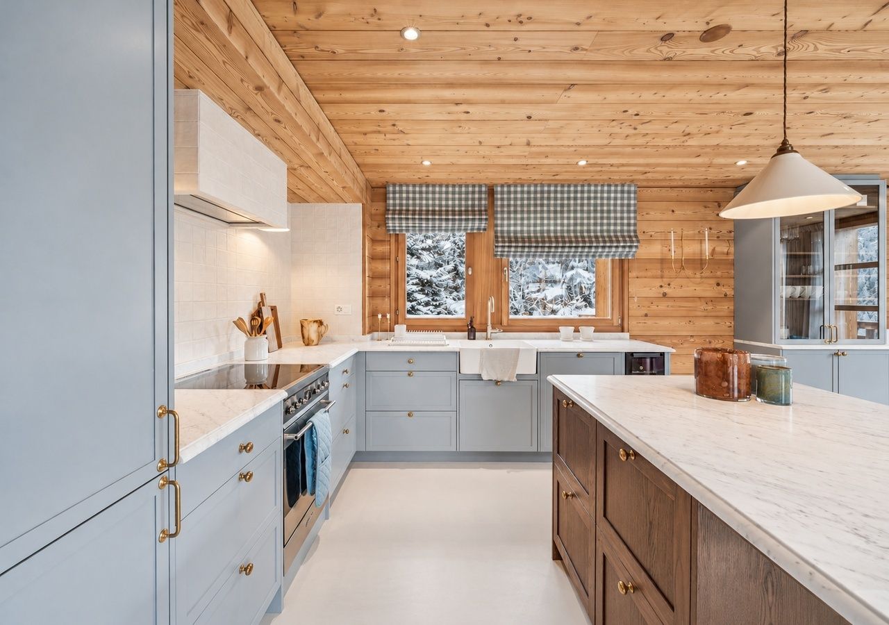Een moderne keuken met houten plafond, een centraal eiland en een raam met uitzicht op besneeuwde bomen.