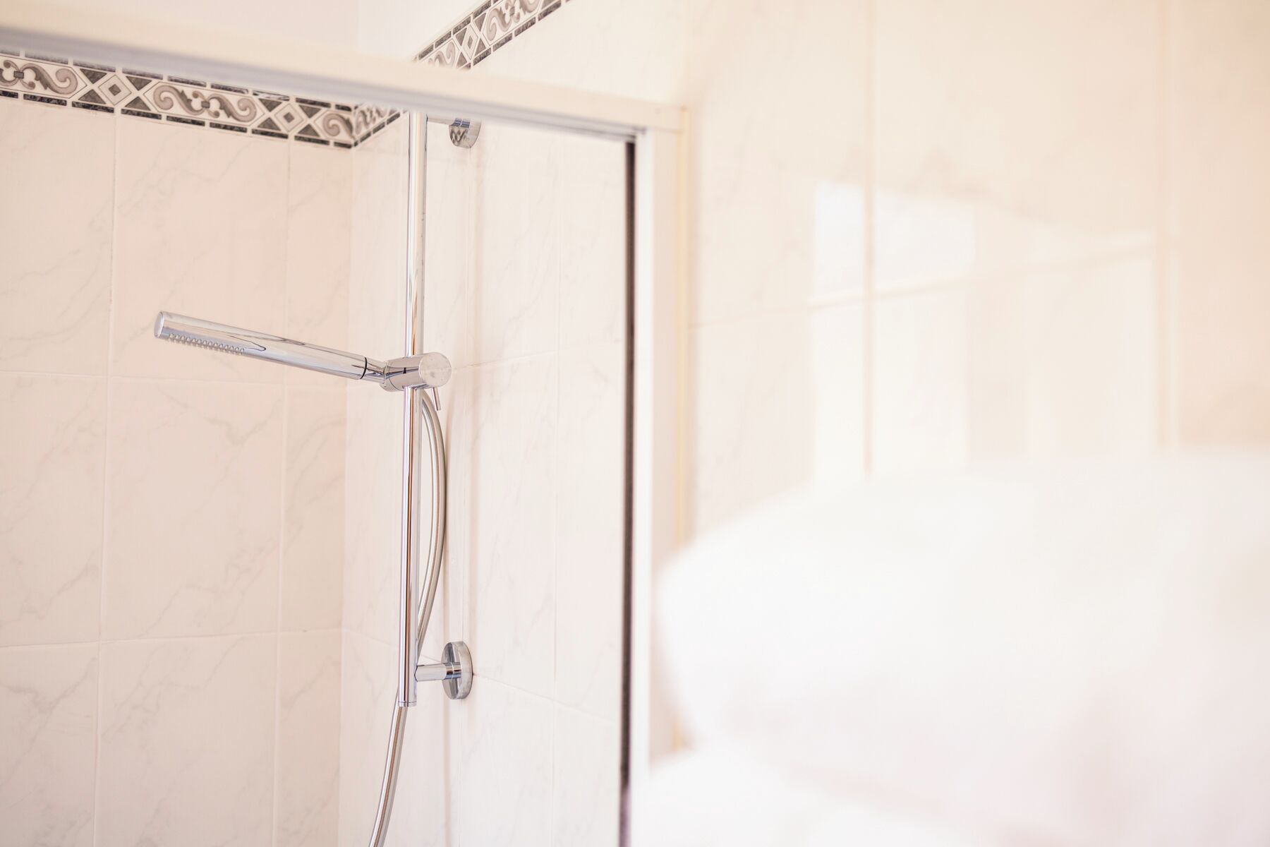 A shower with a glass door and a chrome faucet.