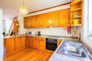A kitchen with wooden cabinets, a microwave, a coffee maker, and a stainless steel sink.