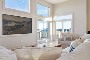 A spacious living room with a large painting, a sofa, and a balcony with a view. - Ocean + ICW Views 7BR, Pool, Cabana, Elevator (Surf City)