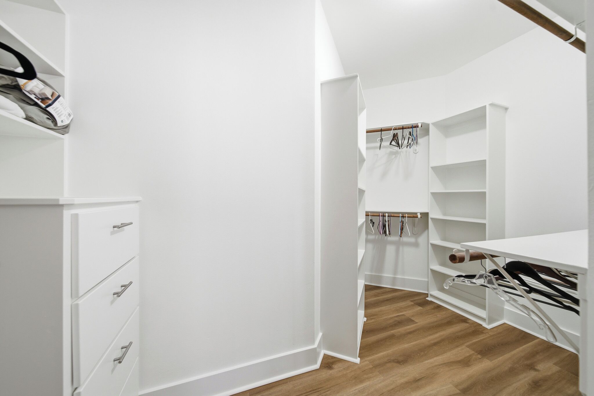 Een witte kast met open planken, een hanggedeelte en een houten vloer.