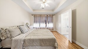 A bedroom with a bed, a ceiling fan, a window with curtains, and a door. - NRG Stadium Steps Away- Perfect World Cup Stay w/ Parking and Security Gates (Houston)