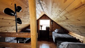 Un dormitorio estilo loft con vigas de madera, un ventilador de techo y dos camas.