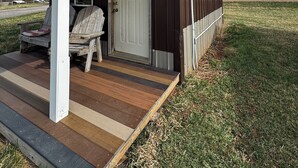 Una pequeña construcción de madera con un porche, una puerta y un letrero.