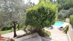 A pool area with steps leading down to a pool, surrounded by trees and a stone wall. - Your Provençal Escape among Olive Trees, with a Private Pool (CALLAS)