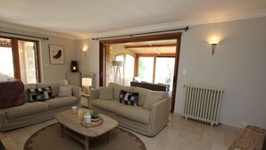 A living room with a sofa set, a coffee table, a lamp, a radiator, and a view through an open door. - Your Provençal Escape among Olive Trees, with a Private Pool (CALLAS)