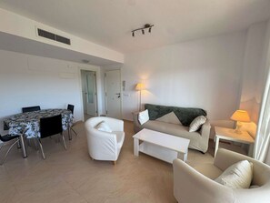 A living room with a dining table, two sofas, a coffee table, and a lamp. - Beachnear modern apartment with community pool (Dénia)