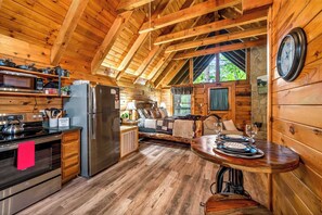 Interior de una cabaña de madera con cocina, comedor y una sala de estar acogedora.