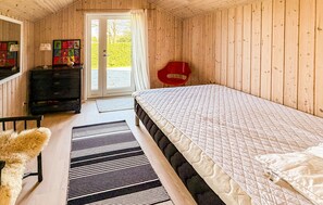 Ein Zimmer mit Holzboden, einem Bett, einem Schminktisch, einem roten Stuhl und einer Tür, die nach draußen führt.