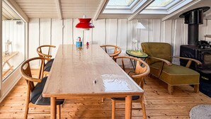 A wooden dining table with chairs, a red pendant light, a green armchair, and a wood-burning stove. - Gorgeous home in Egernsund with WiFi (Egernsund)