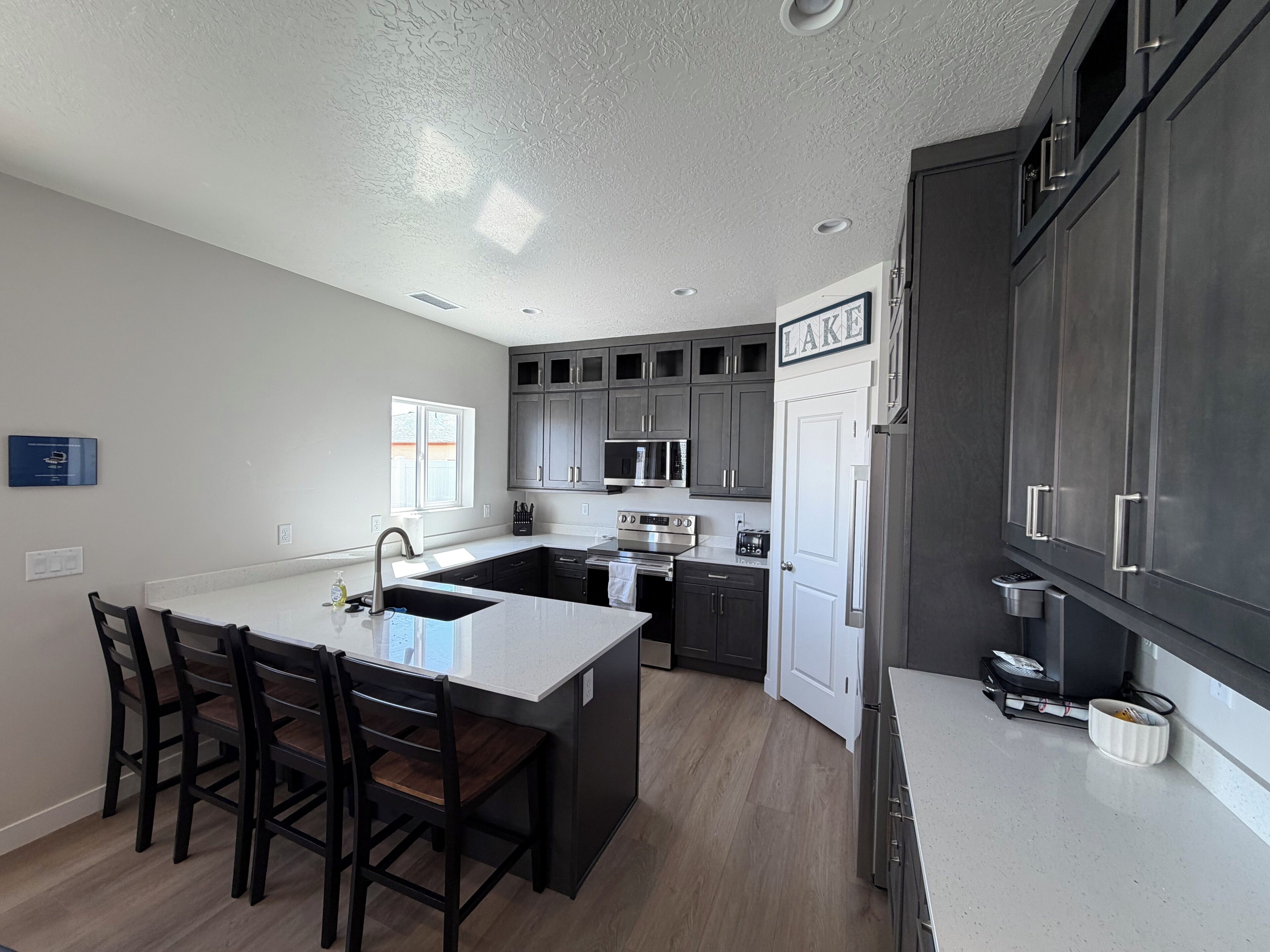 A modern kitchen with a central island, dark cabinets, and a white countertop.