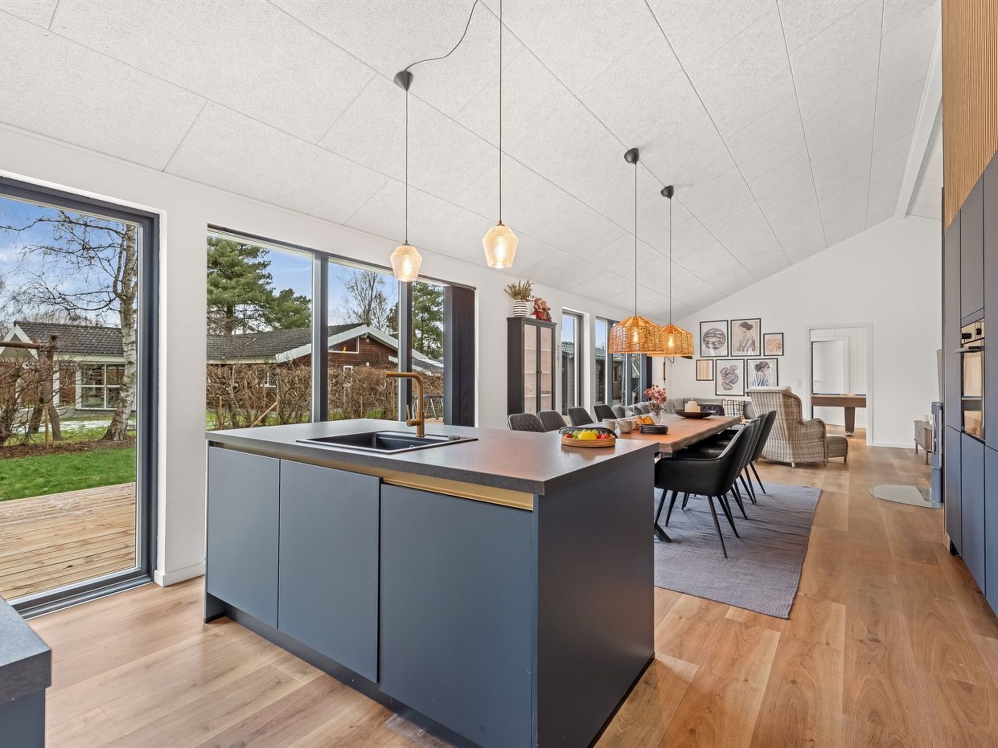 A modern kitchen with a large island, pendant lighting, and a view of the outdoors.