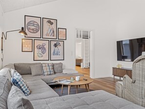 Ein modernes Wohnzimmer mit einer Eckcouch, einem runden Couchtisch und einem Flachbildfernseher.