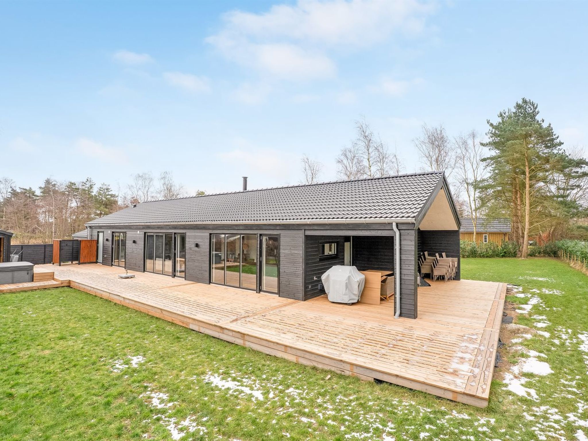 A modern house with a patio, large windows, and a covered outdoor seating area.