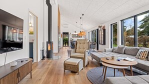 Ein modernes Wohnzimmer mit Kamin, großen Fenstern und einer gemütlichen Sitzecke.