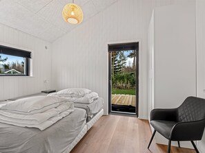 Ein Schlafzimmer mit einem Bett, einem Sessel, einem Fenster und einer Tür, die zu einem Außenbereich führt.