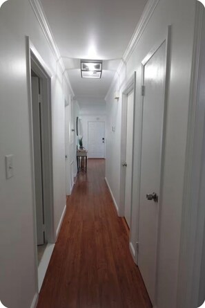 A hallway with white walls and wooden flooring, leading to a door at the end. - Relaxing 3BR Near RAFB with AC & WiFi (Warner Robins)
