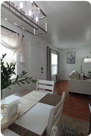 A dining area with a white table, chairs, and a chandelier. There is a white couch and a painting on the wall. - Relaxing 3BR Near RAFB with AC & WiFi (Warner Robins)