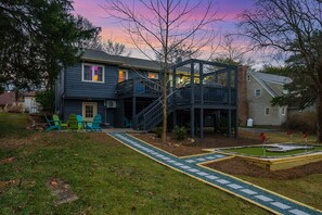 A two-story house with a deck, a small garden, and a pathway leading to the front door. - 5BR Movie Theater, Hot Tub, Mini Golf, Game Room! (McGaheysville)