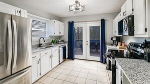 Una cocina moderna con electrodomésticos de acero inoxidable, armarios blancos y vistas al exterior.