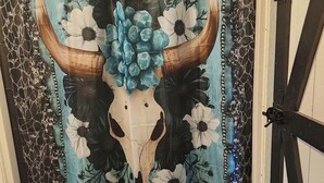 A bathroom with a shower curtain featuring a bull skull and floral design.