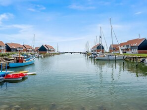 Ein Yachthafen mit angestaubten Booten, Häuser mit roten Dächern und einem klaren Himmel.