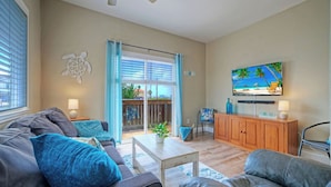 A living room with a sofa, coffee table, and TV. - Sea Gypsy by Avantstay 1BR Coastal Condo + Shared Pool Short Walk to Beach + Mins to Port A (Corpus Christi)