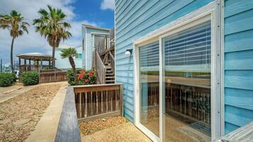 A coastal building with a wooden deck, a covered patio, and a large sliding glass door.