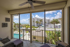 Ein Balkon mit Blick auf einen Pool, Palmen und einen Parkplatz.