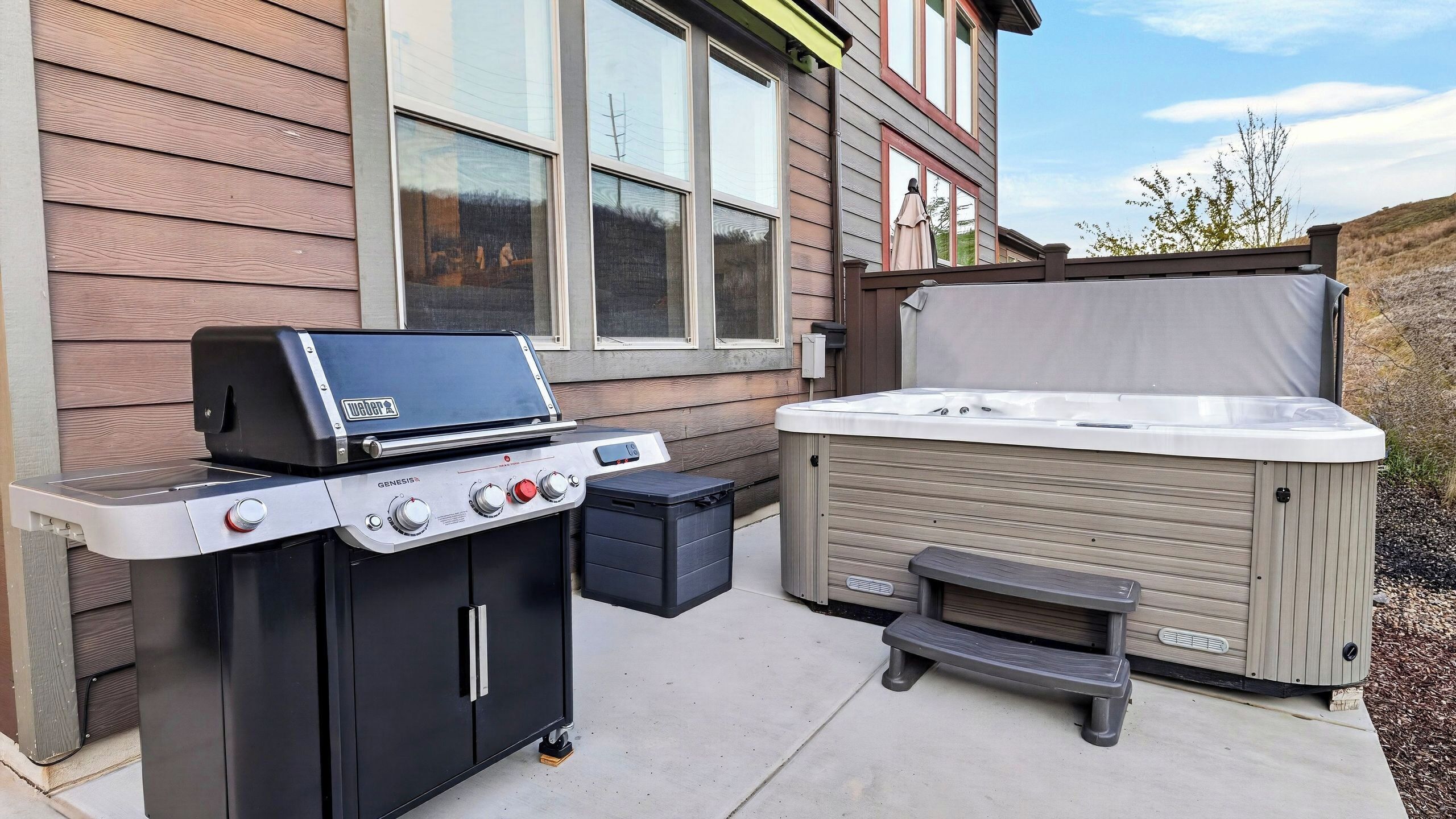 An outdoor grill and hot tub setup in front of a house.