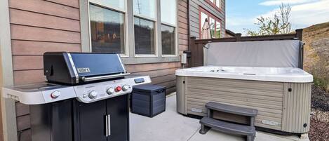 An outdoor grill and hot tub setup in front of a house.