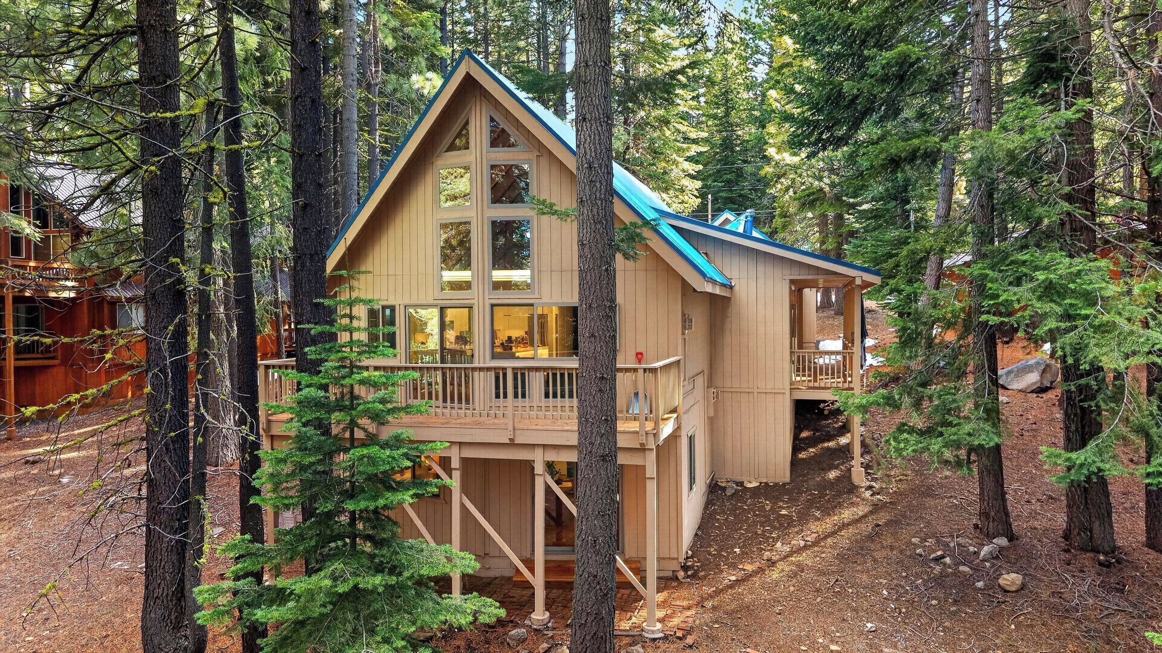 A wooden cabin with a balcony, surrounded by trees.