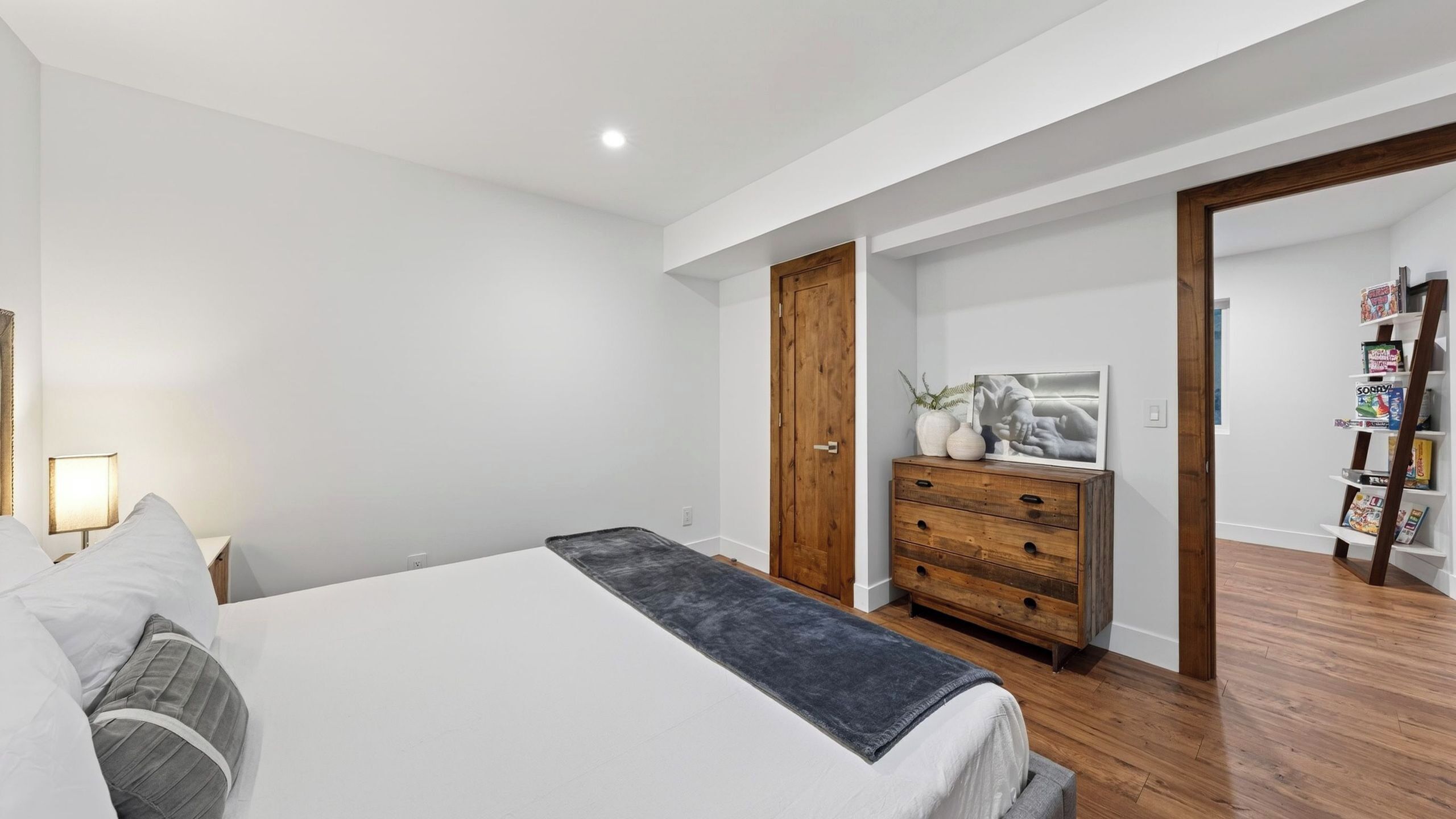 Une chambre à coucher avec un lit, une commode en bois, une porte et une bibliothèque.