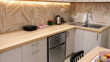 A modern kitchen with a wooden herringbone backsplash, stainless steel appliances, and a wooden countertop.