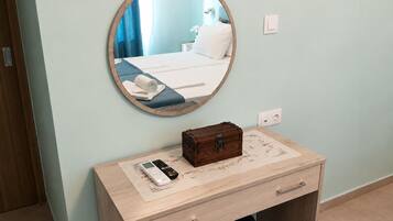 Una habitación de hotel con una cama, una mesita de noche con un control remoto, una pequeña caja de madera y un espejo redondo en la pared.