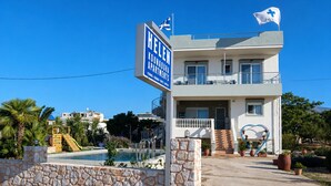 Ein Gebäude mit einem Schild, das 'HELE KOUNADOU APARTMENTS' zeigt, und einer Flagge.