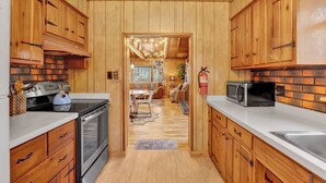 Una cocina con armarios de madera, estufa y microondas.