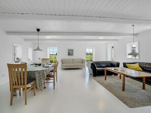 Ein geräumiger Wohnbereich mit Esstisch, Stühlen, einer Couch und einem Couchtisch.