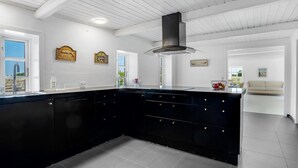 Eine moderne Küche mit einer schwarzen Kochinsel, weißen Wänden und einer Holzbalkendecke.
