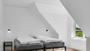 Ein Schlafzimmer mit einem Hochbett, zwei Nachttischen, einem Fenster mit Aussicht und einer schrägen Decke.