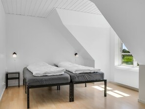 Ein Schlafzimmer mit einem Hochbett, zwei Nachttischen, einem Fenster mit Aussicht und einer schrägen Decke.
