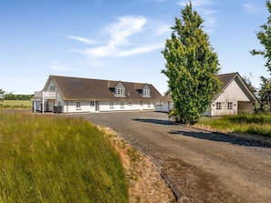 Ein großes, eingeschossiges Gebäude mit einer Schotterauffahrt und einem grünen Feld im Vordergrund.