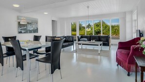 Ein modernes Interieur mit Essbereich, Sofa und einem roten Sessel.