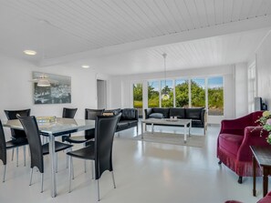 Ein modernes Interieur mit Essbereich, Sofa und einem roten Sessel.
